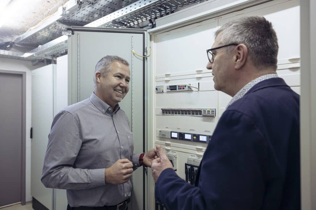 Michael Krammer von Rexel im Gespräch mit Rainer Brade von Siemens vor einem Schaltkasten