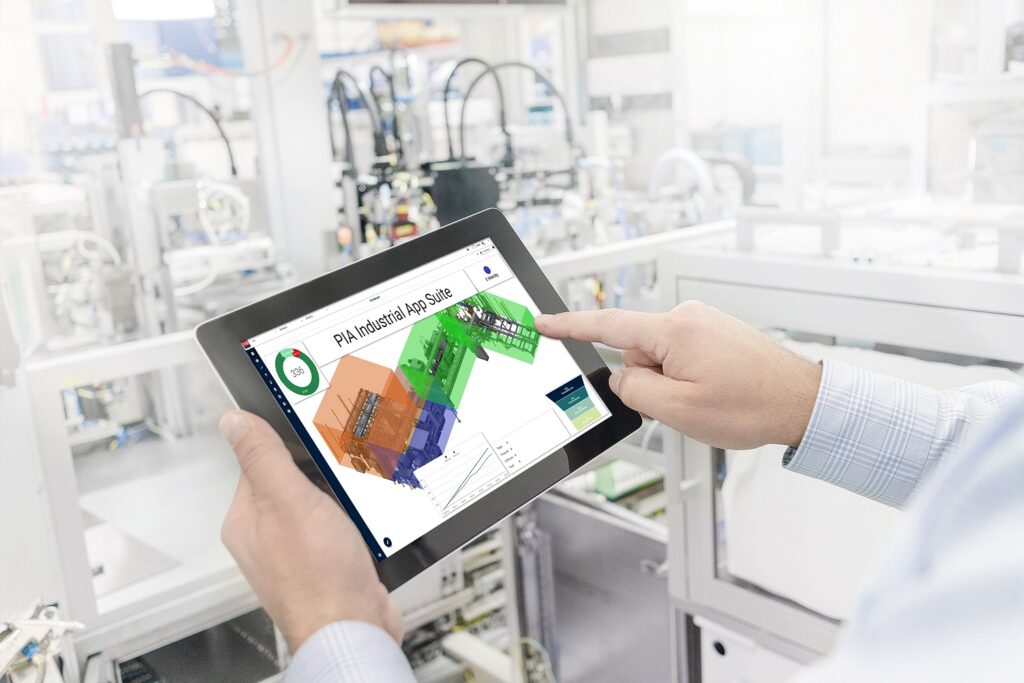 Ansicht einer Anwendung der PIA Automation auf einem Tablet, das ein Mann in der Hand hält, der vor einer Produktionsanlage steht.