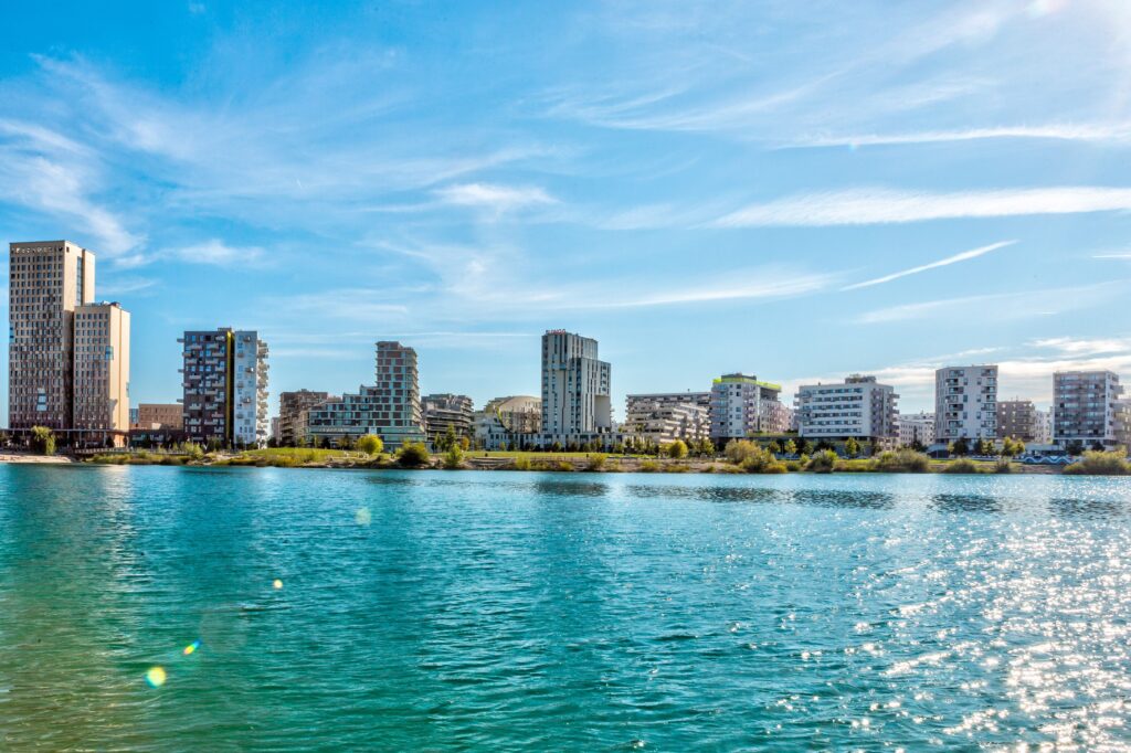 Skyline von aspern Seestadt in Wien bei leicht bewölktem Himmel mit See im Vordergrund