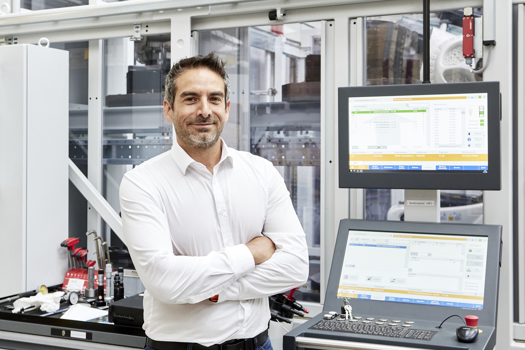 Thomas Burger, Verkaufsleiter Flexible Fertigungssysteme, PROMOT Automation, vor einer digitalen Fertigungsumgebung mit zwei Bildschirmen