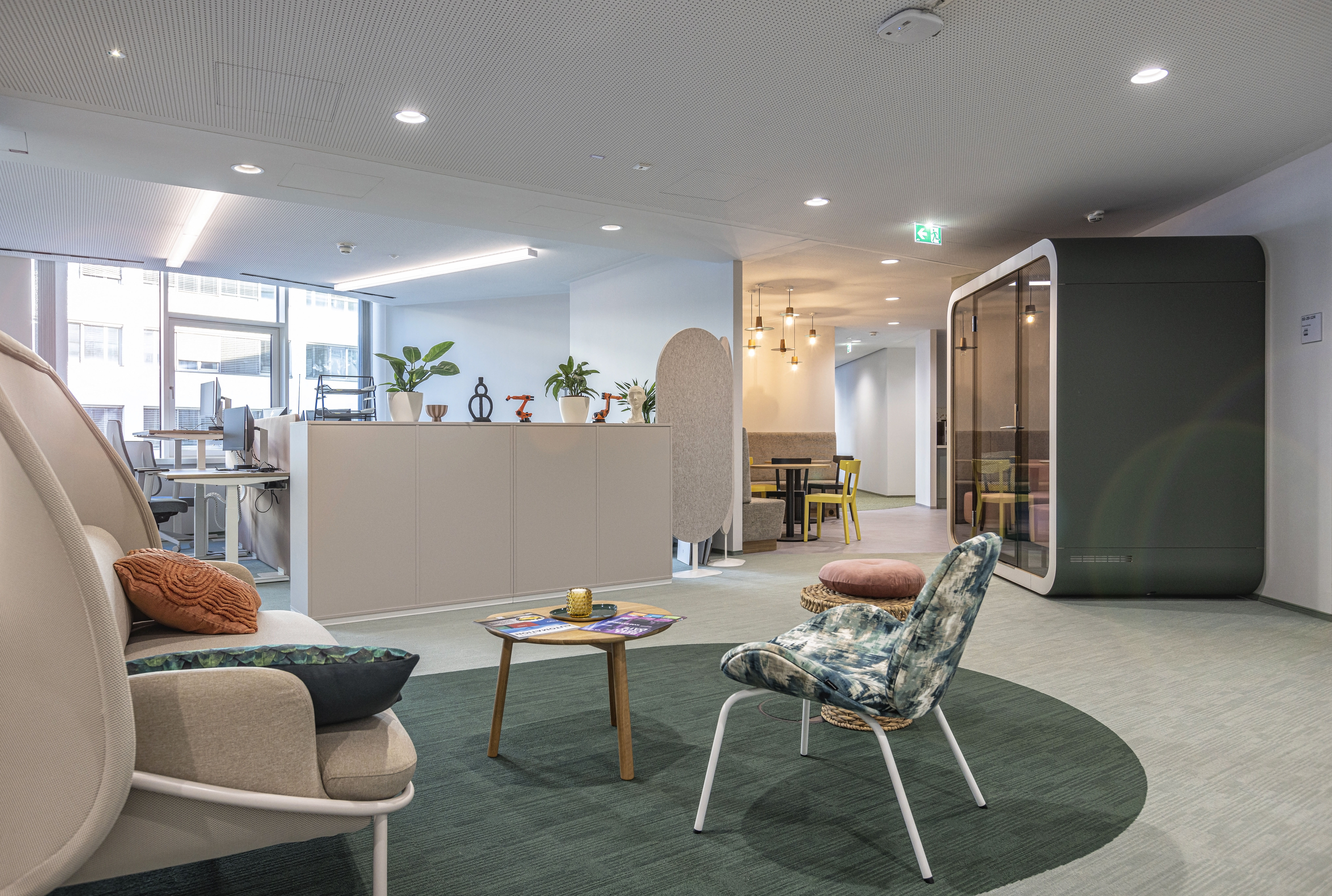 Das Bild zeigt Stühle und Tische auf olivgrünem Teppich in einem Büro am neu eröffneten Standort der Niederlassung Linz.
